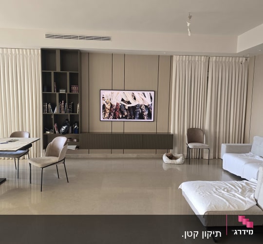 חדר מגורים עם טלוויזיה על הקיר ותאורה תלויה
